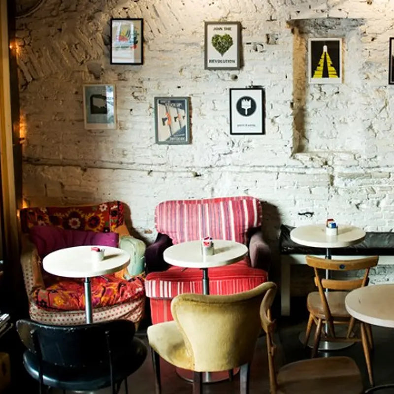 Cozy cafe interior at Barnum Coffee in Rome, Italy with colorful chairs and tables against a textured wall.