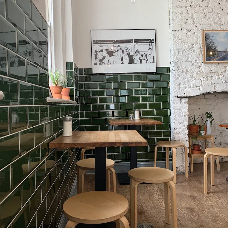 Third wave coffee shop interior with green tiled walls, wooden tables, and stools. Dublin, Ireland.