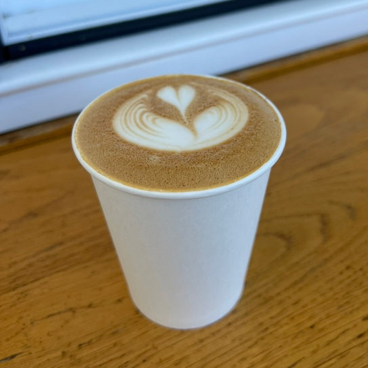 Cappuccino with latte art in a white cup on a wooden surface on Big Island Hawaii